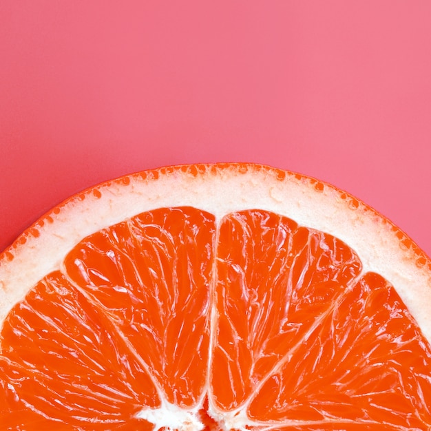 Top view of a one grapefruit slice on bright light pink color