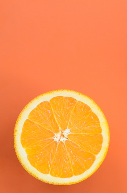 Top view of a one orange fruit slice on bright background in orange color. A saturated citrus texture image