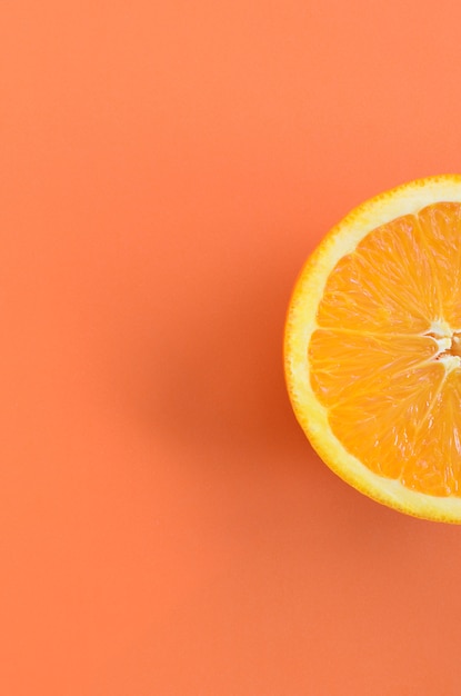 オレンジ色の明るい背景に1つのオレンジ色の果物のスライスの平面図です。