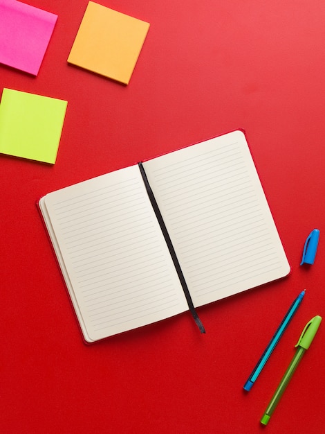 Top view of an open blank red notebook in the center