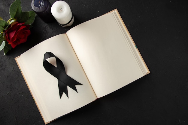 Top view of open book with black mourning bow on dark wall