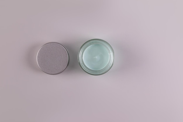 Top view of an open jar of a cosmetic product with a delicate blue texture for everyday face and body skin care spa massage Gray background