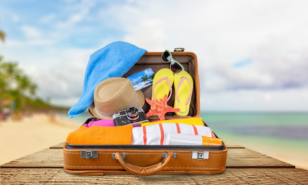 top view of an open suitcase with full of summer stuff on blue background