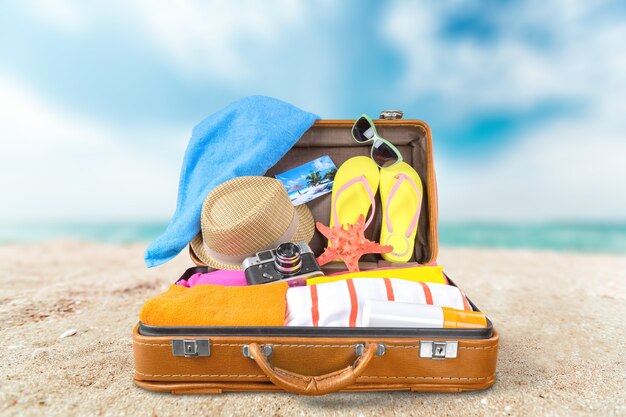 top view of an open suitcase with full of summer stuff on blue background