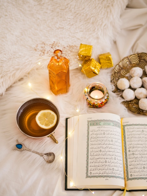 Photo top view opened quran with lemon tea and pastries