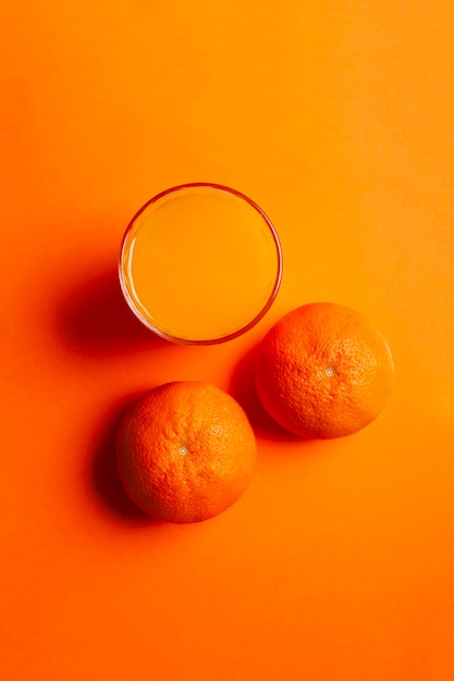 Photo top view of orange juice with oranges on orange background healthy drink concept