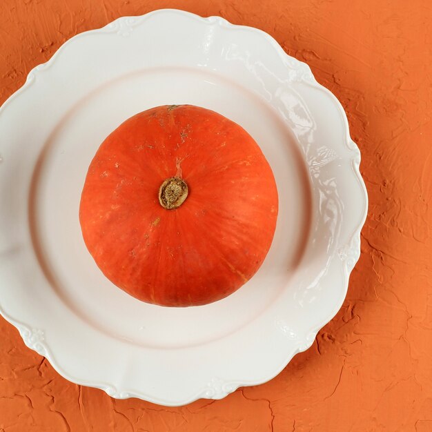 Zucca arancione vista dall'alto su piatto bianco