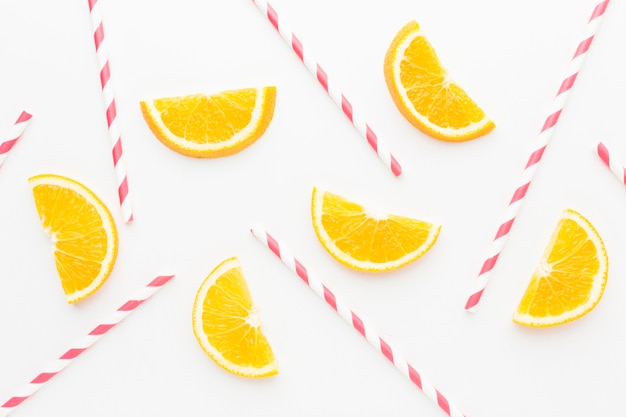Photo top view of orange slices with straws for juice