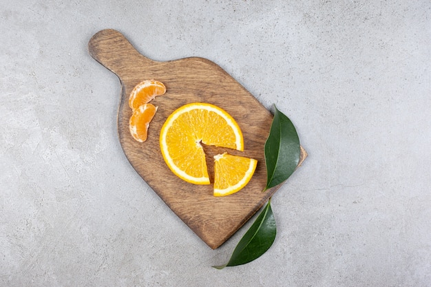 Top view of orange and tangerine slices on wooden cutting board.