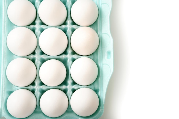 흰색 배경에 있는 보호용 용기에 있는 유기농 계란의 상단 보기가 닫힙니다.