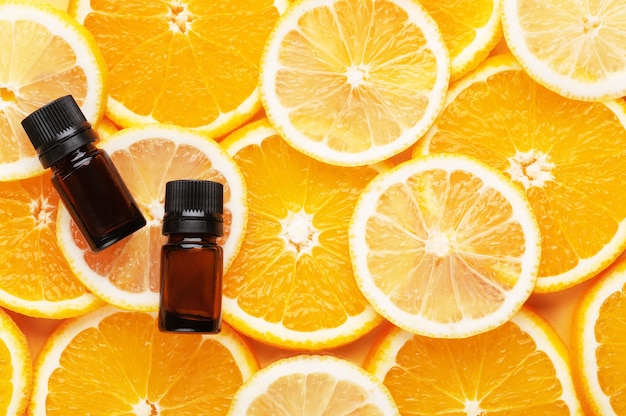 Top view of organic essential oil. Natural cosmetics product. Glass containers with liquid. Slices of orange and lemon on background, place for text. Eco-friendly cosmetics and aromatherapy concept.