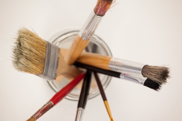 Top view of paint brushes in glass jar against white surface