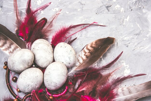 Top view painted easter eggs with stone effect and bright feathers