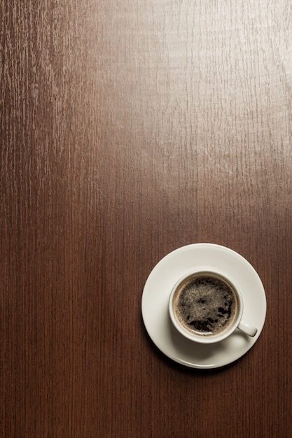 Vista dall'alto di una tazza di carta di caffè nero sul tavolo di superficie in legno