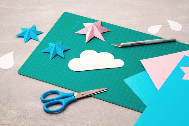 Top view over paper  cut tools, scissors, cutter, cutting mat, and crafted paper objects. DIY trendy project concept