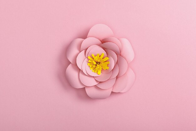 Вид сверху на бумажный цветок на розовом фоне
