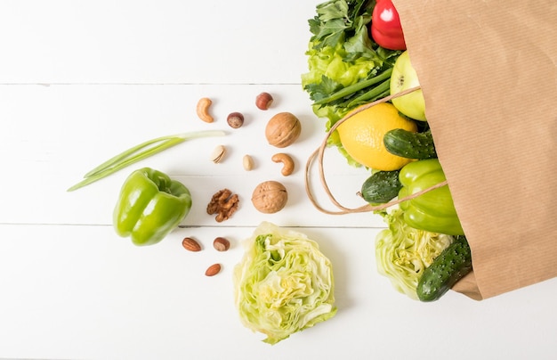 Top view of a paper kraft bag with healthy natural food on a white wooden table. the concept delivery or purchase in the supermarket.