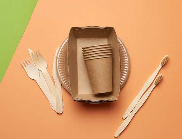 Top view of paper plates and cups from brown craft paper with wooden forks and knive