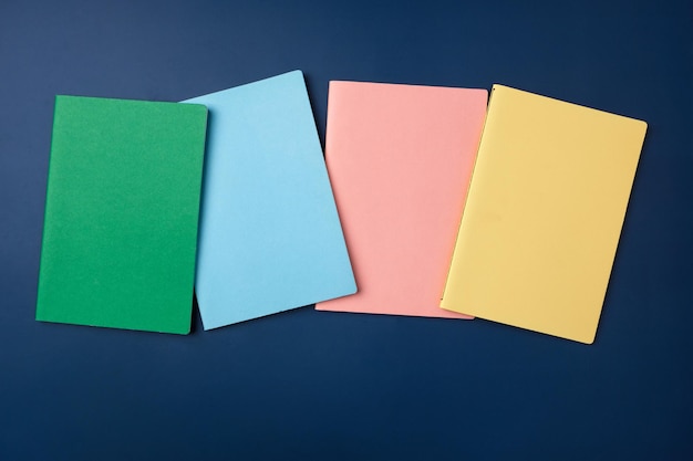 Top view pastel notebook with pencil and stationery on navy blue table background