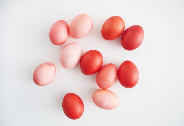 Vista dall'alto delle uova di pasqua dipinte a mano rosa pastello disposte in una composizione minima su sfondo bianco, copia dello spazio