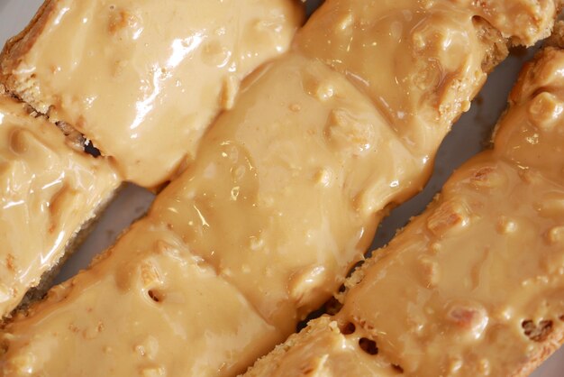 Top view of peanut butter and a bread on plate on black background