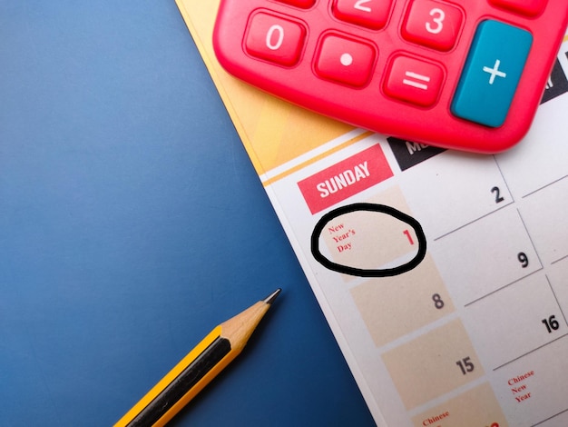 Top view pencil and calculator with a calendar marked with the new year date