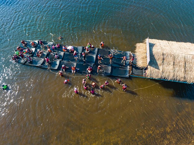 Вид сверху Люди играют в воду возле деревянного плота, плывущего по реке чанабури, Таиланд