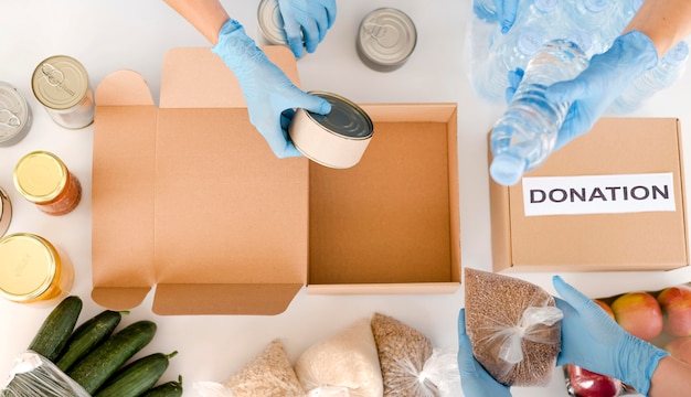 Photo top view of people preparing box with food donation