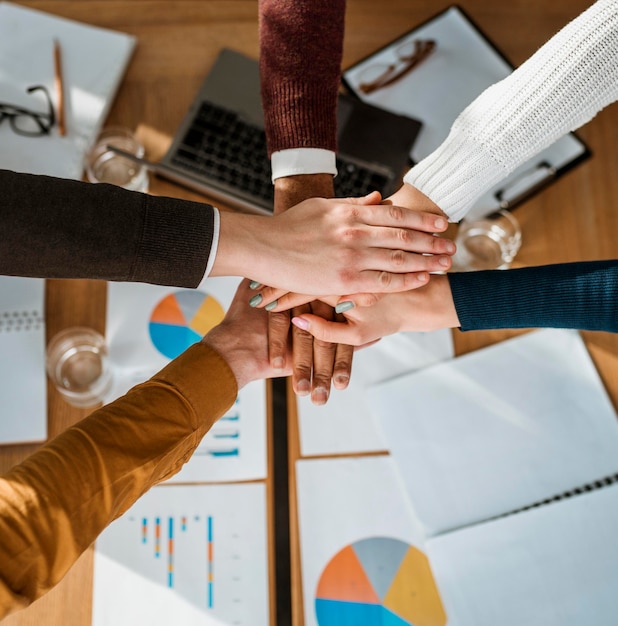 Top view of people putting hands together in agreement during meeting