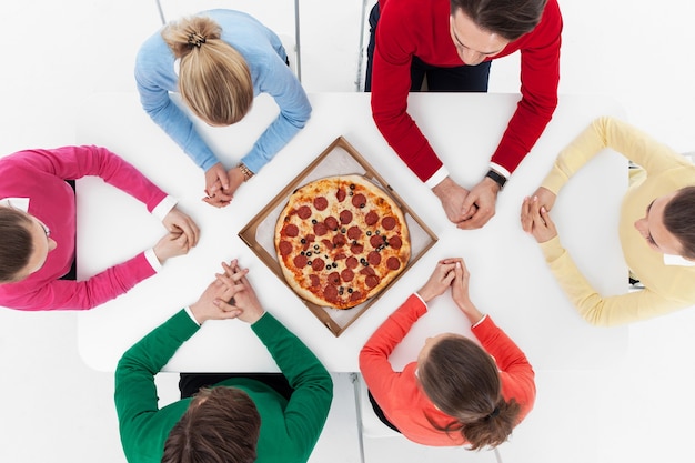 Top view of people sitting around the table with pizza