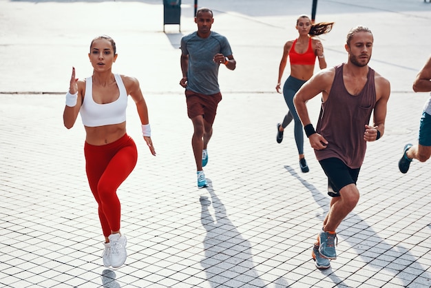 Top view of people in sports clothing jogging while exercising on the sidewalk outdoors