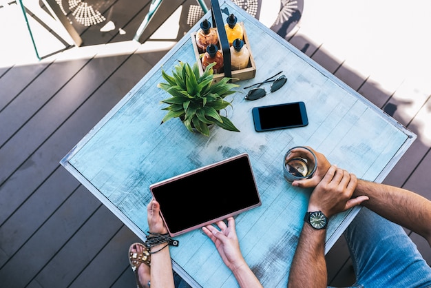 Top view of people with gadgets on a table outside