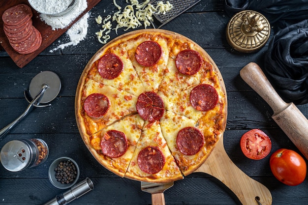 Photo top view of pepperoni pizza on a black wooden backdrop