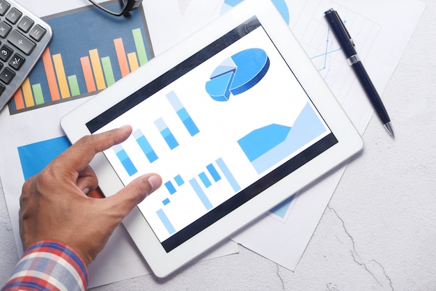 Photo top view of person hand analyzing charts on digital tablet