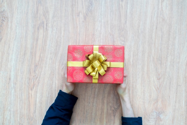 Вид сверху на руки человека, держащего подарочную коробку с праздничным подарком
