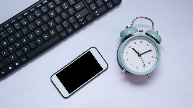 Top view of phone keyboard and alarm clock with white background