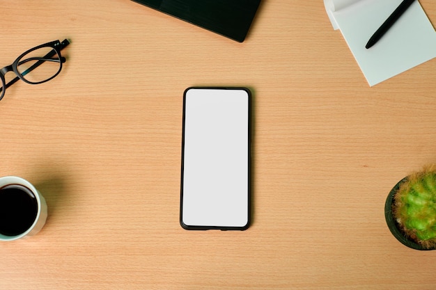 Top view of a phone with a group of business objects on a wooden desk. Copy space, mock up