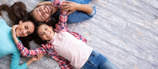 Foto la foto vista dall'alto di una giovane e bella famiglia felice sdraiata sul pavimento si diverte e sorride mentre guarda la fotocamera