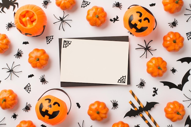 Top view photo of black envelope cobweb on white card pumpkin\
baskets candy corn straws spiders and bats silhouettes on isolated\
white background with blank space