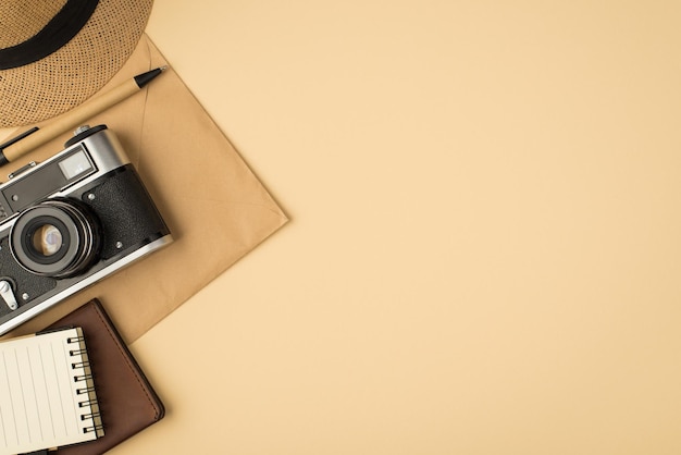 Top view photo of cap pen notebook passport cover and camera on craft paper envelope on isolated beige background with copyspace