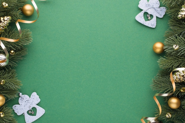 Foto vista dall'alto di palle di albero di natale in oro e argento giocattoli coni angeli piccole campane e serpentine su rami di pino su sfondo verde isolato con spazio vuoto