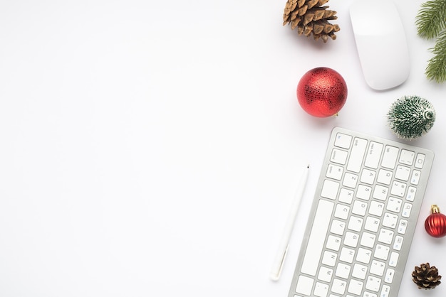 Foto vista dall'alto della tastiera del mouse del computer della penna rossa dell'albero di natale delle palle del giocattolo dell'abete del ramoscello della pigna su fondo bianco isolato con lo spazio vuoto