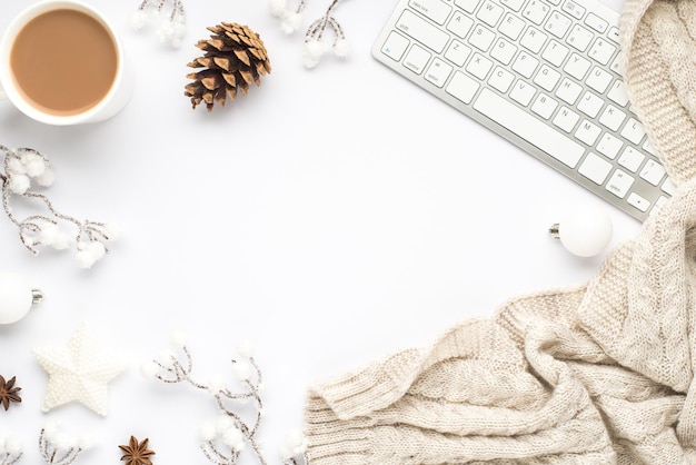 Foto vista dall'alto della tazza della tastiera del bere caldo bianco decorazioni per l'albero di natale palle stella ramoscelli di neve cono anice e sciarpa su sfondo bianco isolato con copyspace nel mezzo