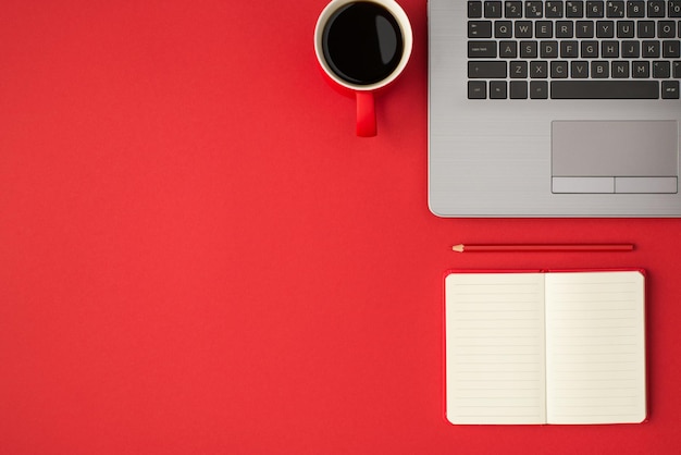 Top view photo of laptop rep planner pencil and cup of coffee on isolated red background with empty space