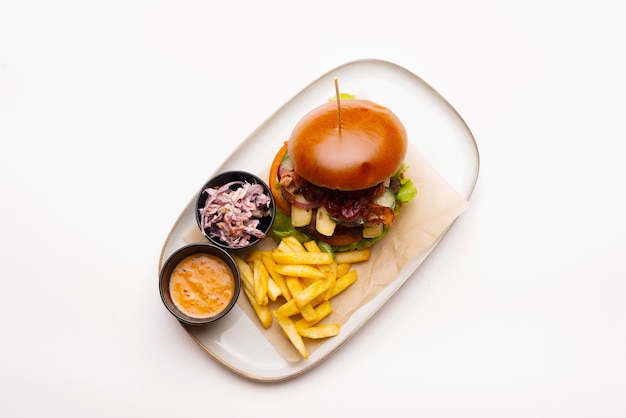 Top view photo of a plate with burger and fries on white background.