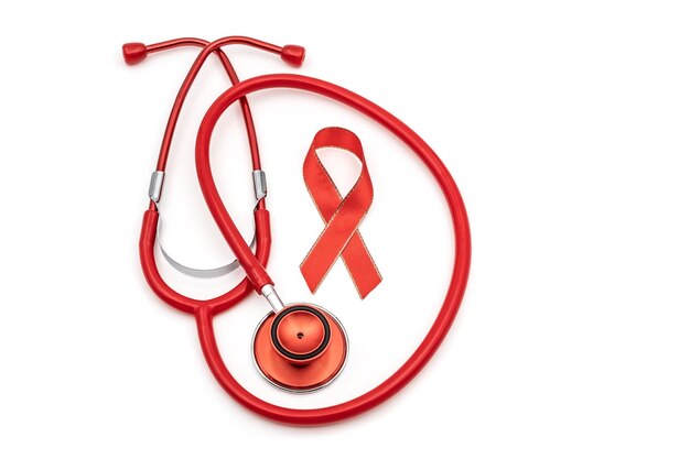 Top view photo of red stethoscope and red silk ribbon symbol of aids awareness on isolated white background with copyspace
