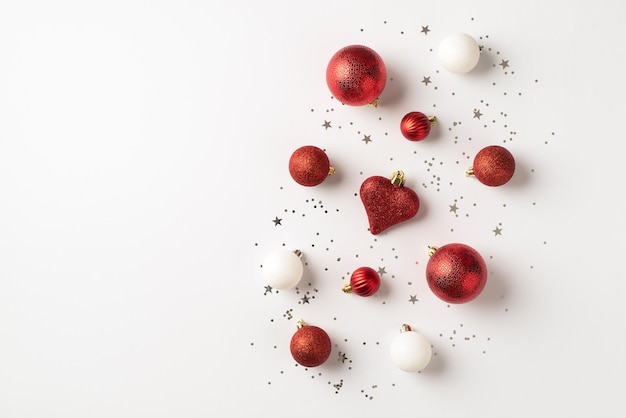 Top view photo of red and white christmas tree decorations balls heart and silver sequins on isolated white background with copyspace