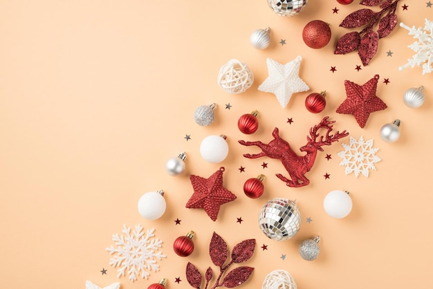 Foto vista dall'alto della composizione di fila rosso bianco e argento decorazioni per l'albero di natale fiocchi di neve palle da discoteca stelle rametti di cervo e coriandoli su sfondo beige isolato con copyspace