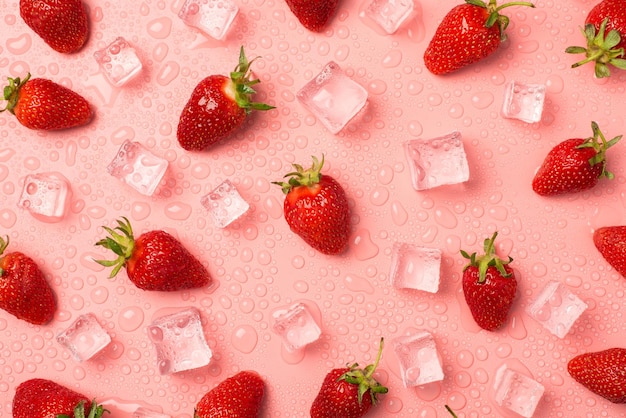 Foto dall'alto di fragole cubetti di ghiaccio e gocce d'acqua su sfondo rosa pastello isolato