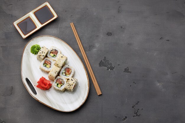 Top view photo of sushi roll with sesame on dark grey background